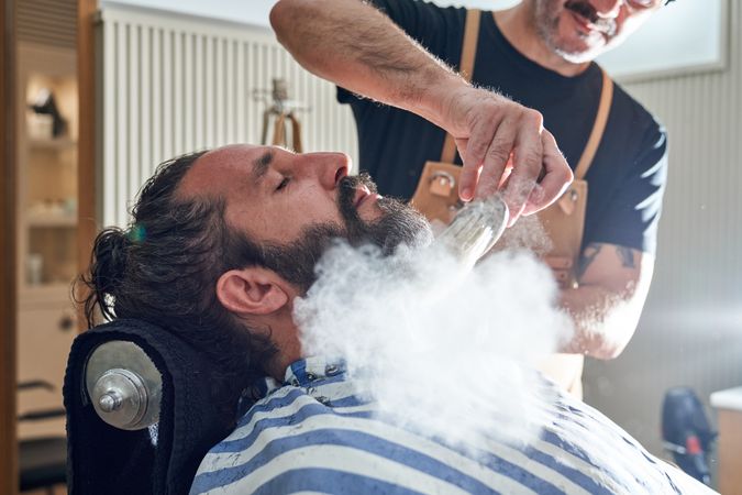 Hairdresser applying powder to customer in barbershop
