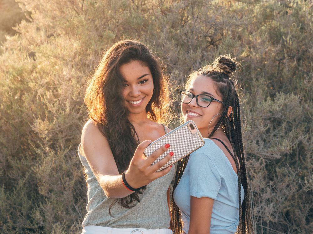 Smiling trendy young women taking selfie at countryside