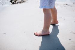 Barefoot child in short on sandy beach