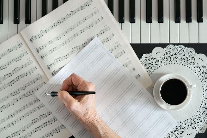 Person writing musical notes on piano