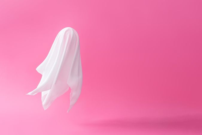Ghost sheet costume against pastel pink background