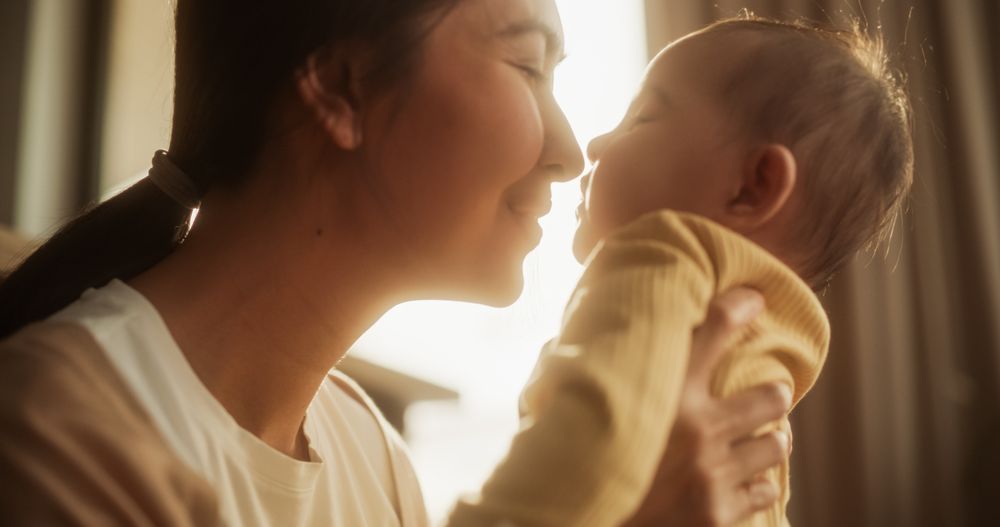 Motherly Affection Concept: Close-Up Portrait of a Cute Asian Baby Laughing and Enjoying Bonding Time
