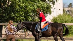 Instructor and young rider with horse during training.