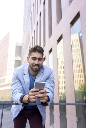 Portrait of Handsome young man smiling using his mobile phone, vertical