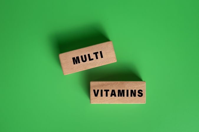 multi vitamins words on wooden blocks isolated on green background