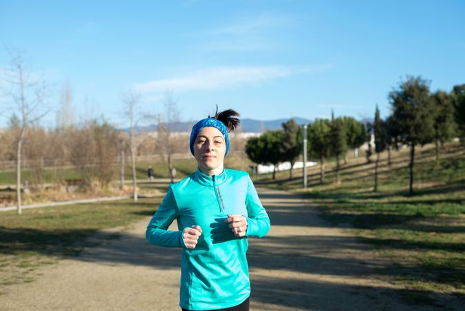 Woman in ear warmers jogging outdoors on sunny fall day