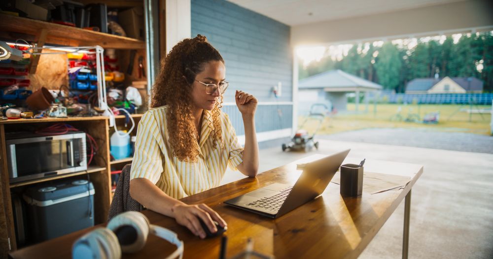 Young Hispanic Female Software Engineer Programming On Laptop Computer In Opened Garage.