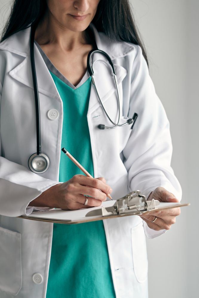 Crop physician in medical robe taking notes on paper