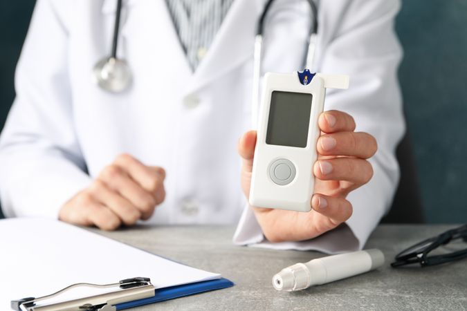 Doctor holds blood glucose meter, close up