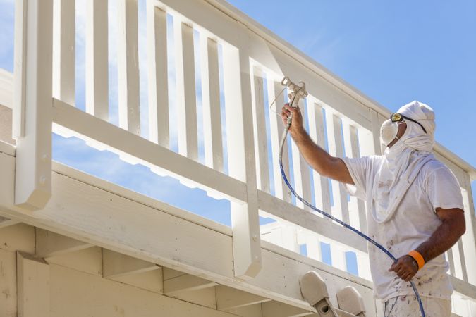 House Painter Spray Painting A Deck of A Home