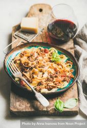 Pasta dinner with minced meat, cheese and red wine on wooden board 4d3dr5