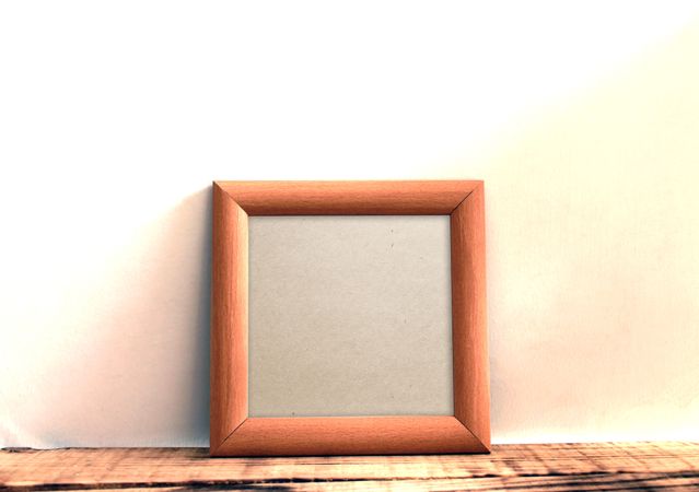 Plain square wooden picture frame leaning against wall mockup
