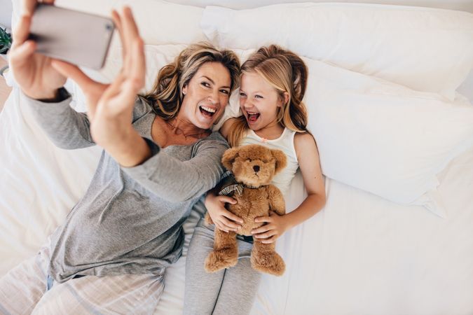 Young family taking selfie on bed at home