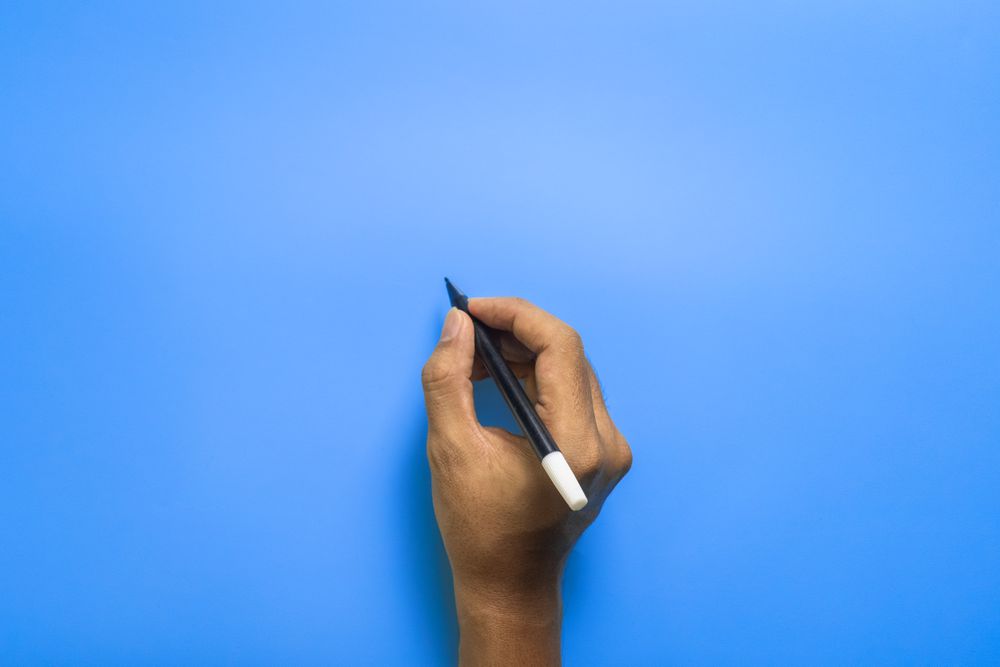 top view of male hand writing on blue blank surface