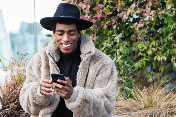 Stylish happy man with smartphone on street