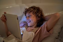Boy having fun while surfing tablet in bathroom