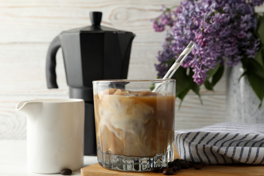 Composition with ice coffee and flowers on wooden background
