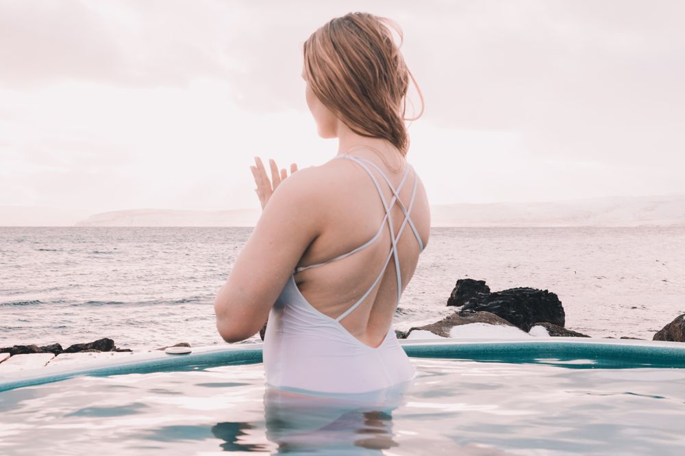Woman sitting in pool near stones