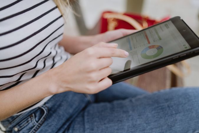 Anonymous woman sitting on bench and using tablet