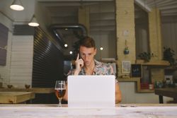 Man talking on smartphone while browsing laptop