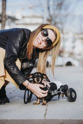 Smiling woman near dog with wheelchair on street