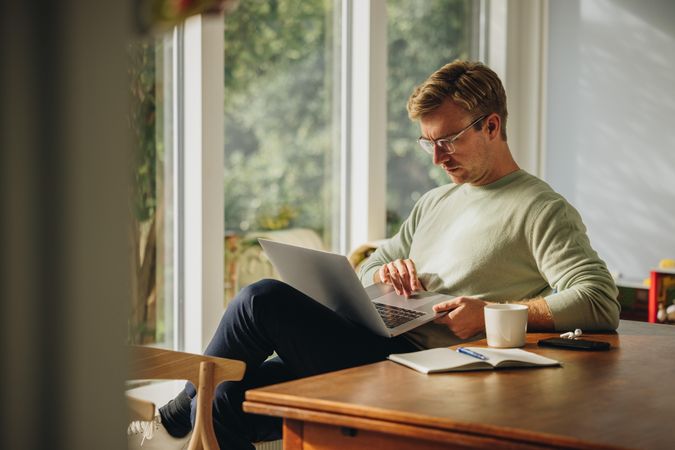 Man starting morning at home checking emails on laptop