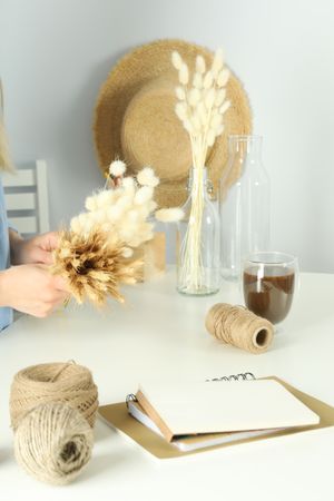 Bright home crafting room with woman working on dried willow arrangement