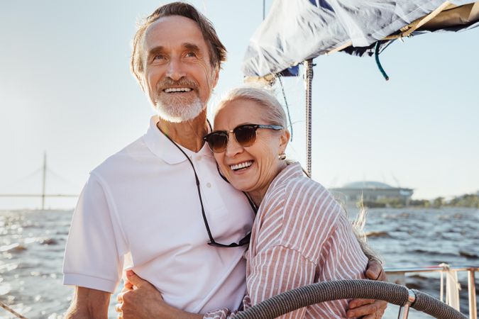 Happy older couple embracing at the helm of a boat