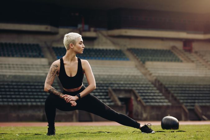 Fitness woman doing warm up exercises stretching her legs on the sides