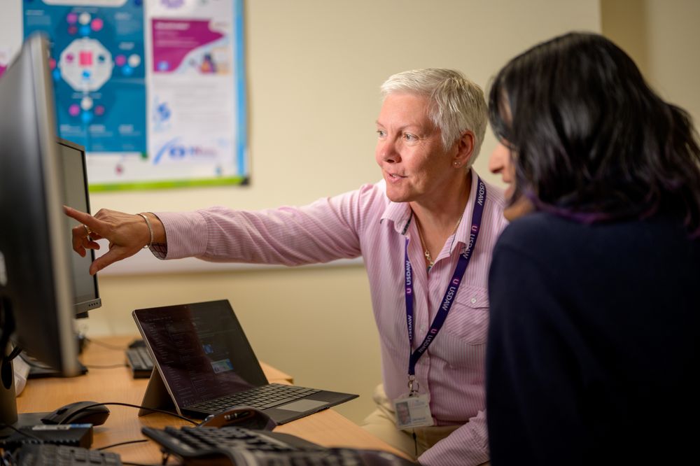 Older woman with short grey hair pointing to a computer screen