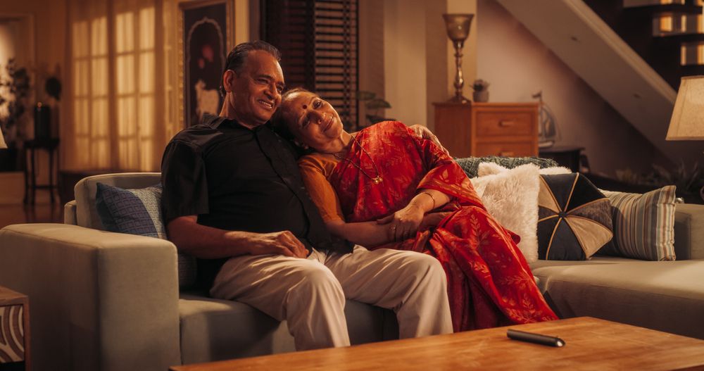 Cozy Time Together: Older Indian Couple Enjoying a Relaxing Evening at Home, Watching Television, Embrace, Smile.