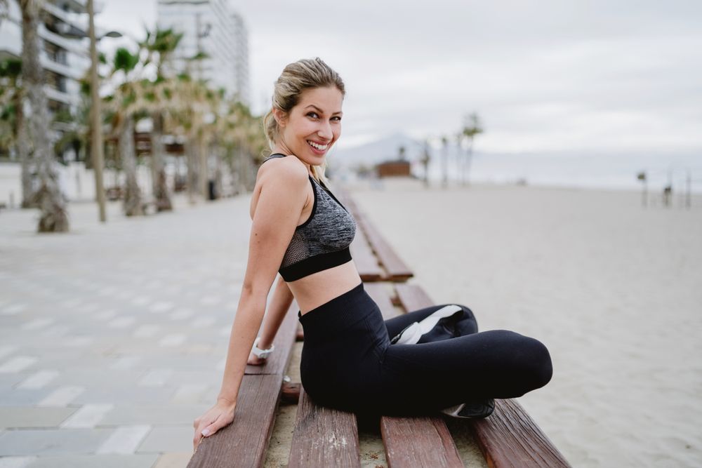 Sportswoman resting in a bench at sandy beach