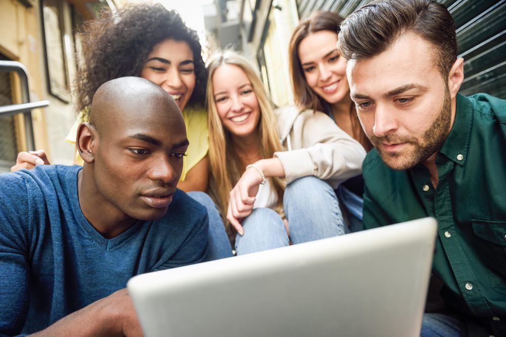Male and female friends engaged by something on digital tablet while sitting on outdoor stairs