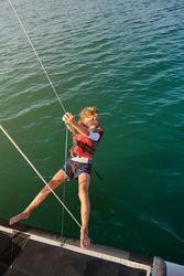 Preteen kid tightening ropes on sails of boat