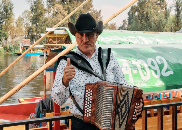 Mexican man in hat playing accordion on riverside