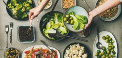 Flat-lay of vegetable salads, legumes, beans, olives, sprouts, hummus on plates