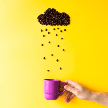 Coffee beans in shape of rainy cloud with purple cup on yellow background