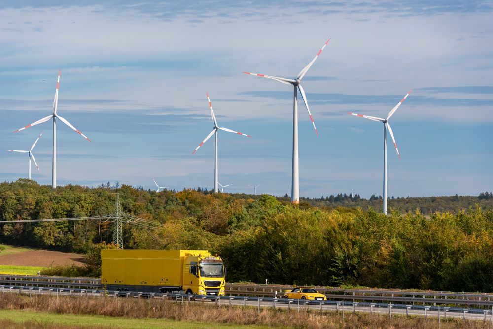 Truck on the highway and wind turbine farm in an autumn scenery in Germany