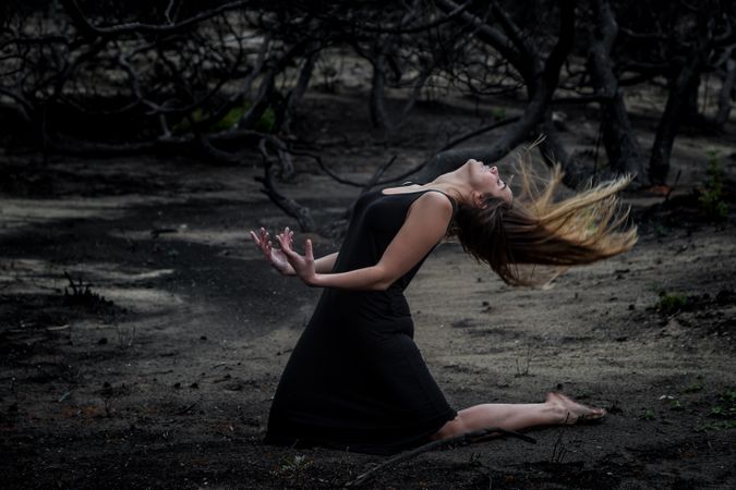Woman posing on ground near dry trees