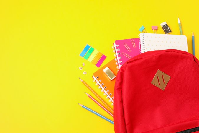 Flat lay composition with backpack and school supplies on color background