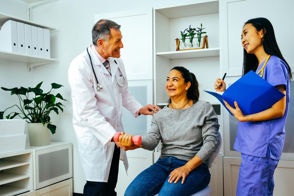 Joking doctor and physiotherapist working with patient during arm rehab exercises