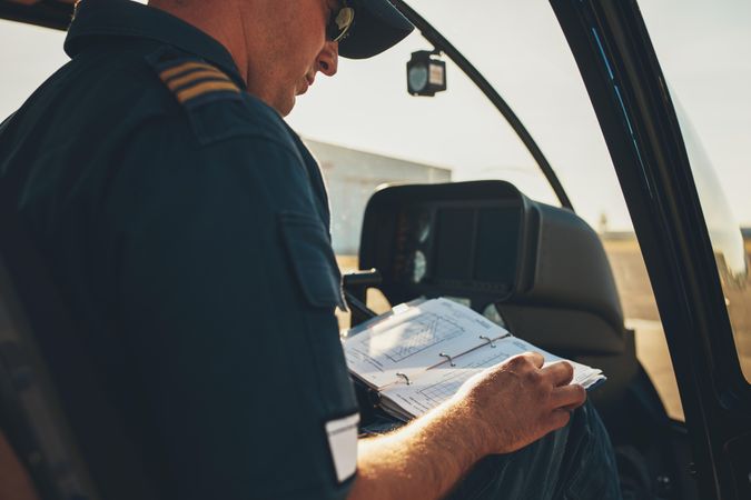 Helicopter pilot is on the ground with bright sunlight with notebook