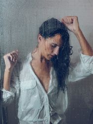 Through glass of woman standing in shower cabin