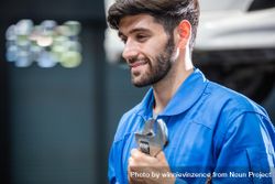 Smiling male mechanic holding wrench at auto garage 5kkjD5