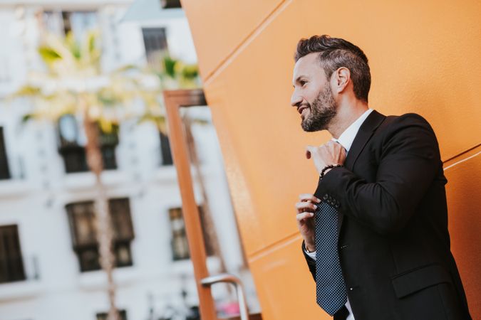 Adult stylish man in costume near orange wall