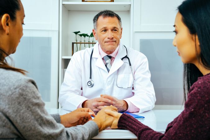 Serious doctor sharing news with two patients in medical office