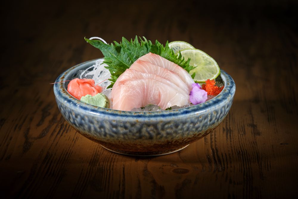 Bowl with delicious sashimi on wooden table