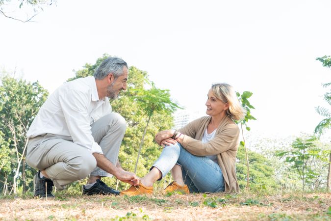 Affectionate mature man tying shoe of woman in park