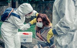 Doctors putting protective mask on woman infected with a virus