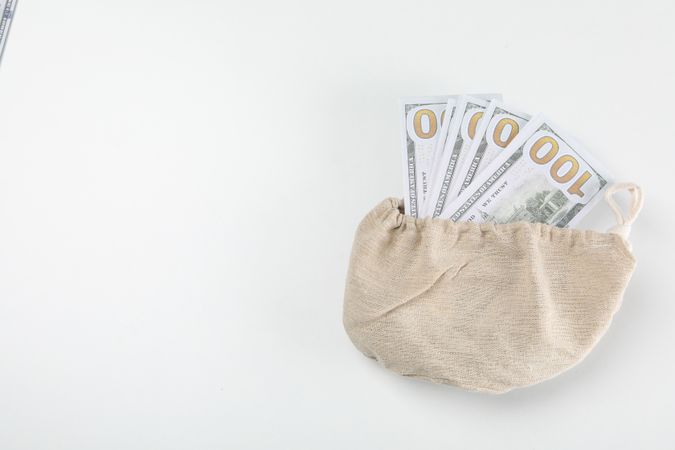 A bundle of 100 bucks in a bag on a light background.